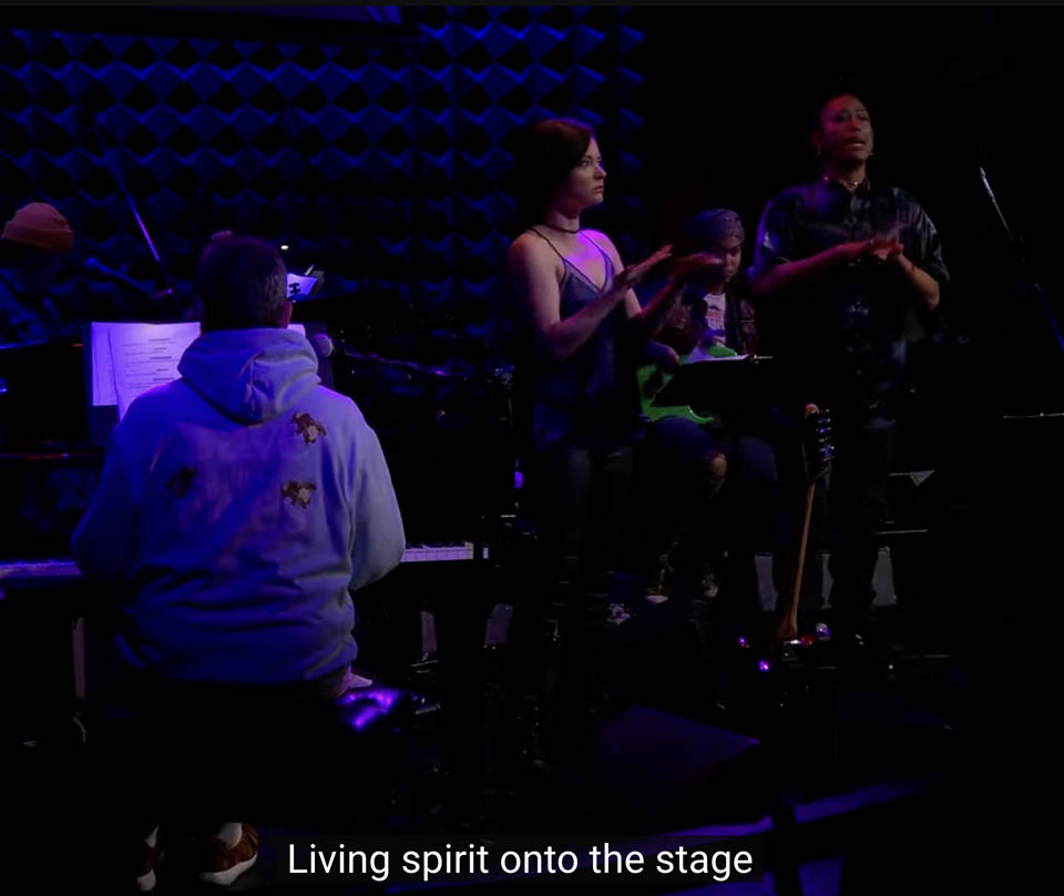 The performers and the words "Living spirit onto the stage" generated on the screen