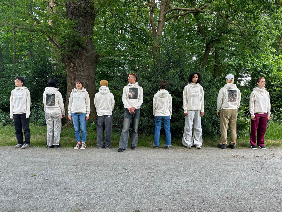 Nine people some facing forward others with their back towards us in a park, by Chloe Bass

